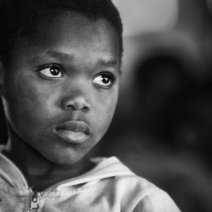 A black and white portrait of a child with a thoughtful expression.